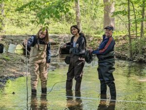 Three volunteers measuring stream velocity.